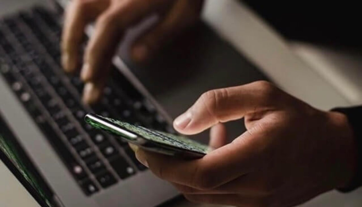 Någon som skriver på sin laptop och håller i en mobil samtidigt