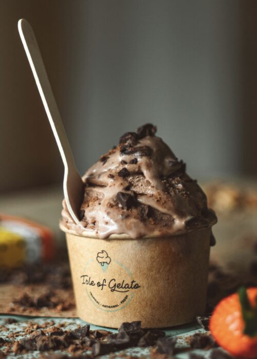 En brun bägare med chokladgelato som har en träsked i sig