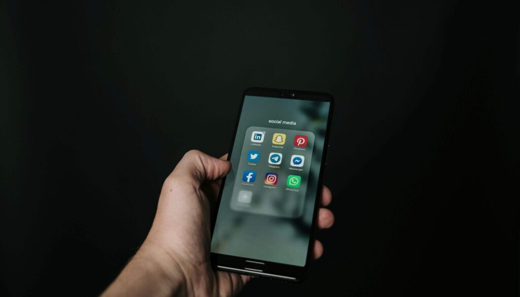 En hand som håller i en mobil som innehåller olika appar