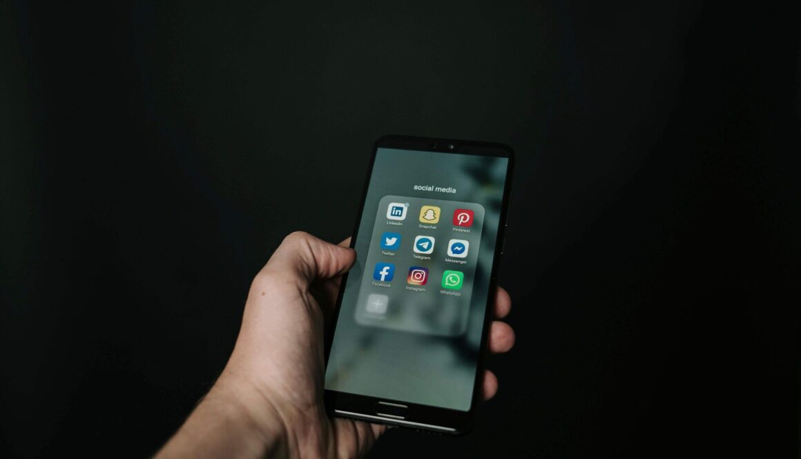 En hand som håller i en mobil som innehåller olika appar